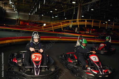 focused multicultural go cart racers driving on indoor circuit, speed racing and motorsport © LIGHTFIELD STUDIOS