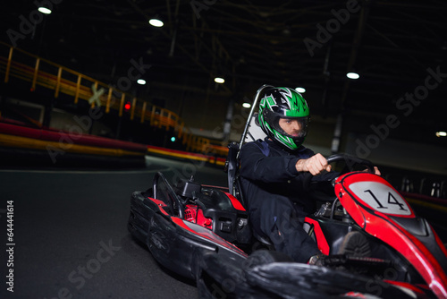 focused racer in helmet and sportswear driving go kart on indoor circuit, adrenaline concept © LIGHTFIELD STUDIOS