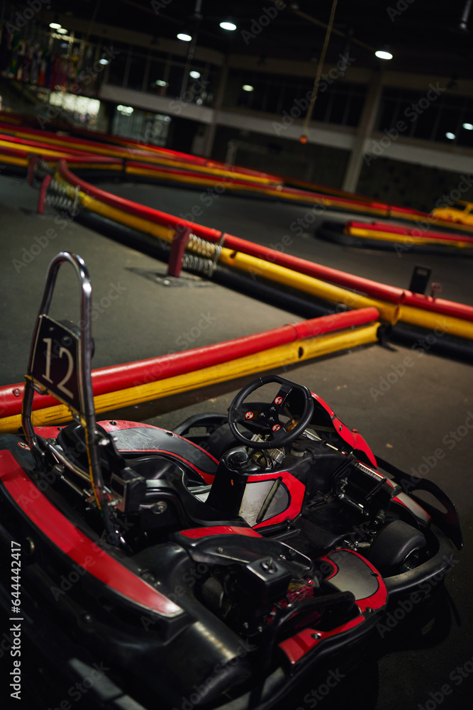 design of red racing car inside of indoor kart circuit, motor race vehicle with number twelve