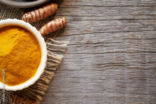 Turmeric powder and root on a rustic wooden background with sopy space photo