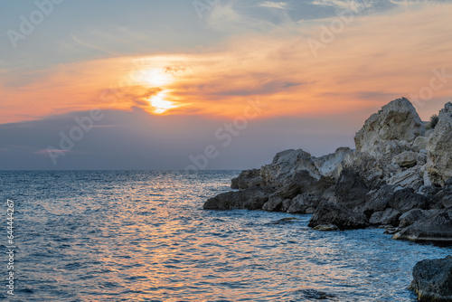 Evening at sea. Thick clouds barely let the rays of the setting sun through.