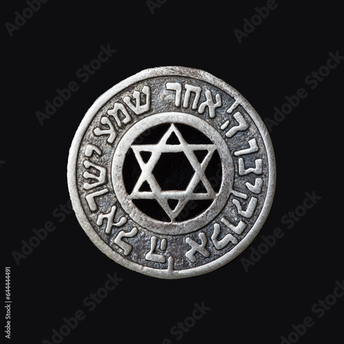 Old silver medallion with the Star of David and the text of the prayer "Hear, oh Israel, the Lord is our God, the Lord is one" on a black velvet background