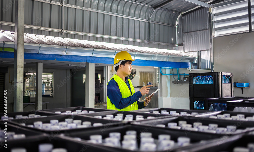 Φωτογραφία In a drink water factory, a tablet computer is being used by a skilled engineer or quality inspector to effectively monitor the process of checking bottled drinking water