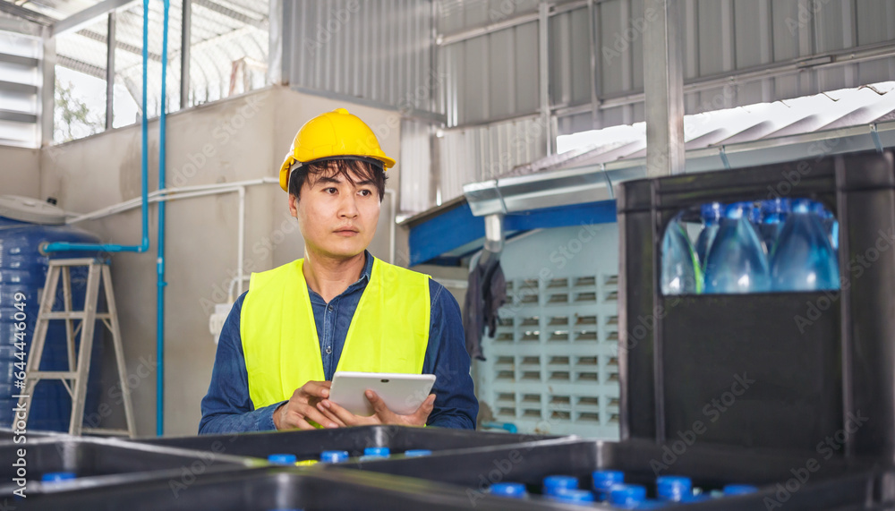 In a drink water factory, a tablet computer is being used by a skilled engineer or quality inspector to effectively monitor the process of checking bottled drinking water. In a drink water factory, a tablet computer is being used by a skilled engineer or quality inspector to effectively monitor the process of checking bottled drinking water.