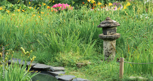 stone lantern among grass on the bank of a pond in a Japanese garden photo