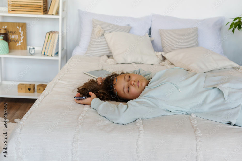Sleeping student teenager lie on bed next to gadgets in the bedroom. Fatigue after study Sleeping student teenager lie on bed next to gadgets in the bedroom. Fatigue after study