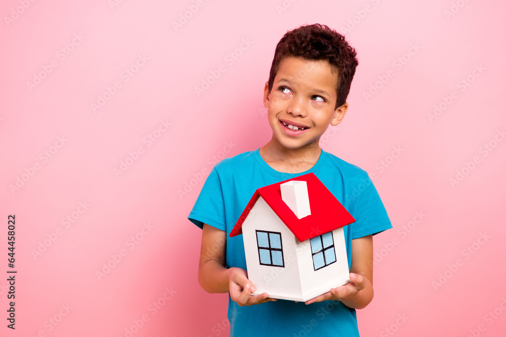 Photo of dreamy adorable small boy wear blue t-shirt holding little toy house looking empty space isolated pink color background Photo of dreamy adorable small boy wear blue t-shirt holding little toy house looking empty space isolated pink color background
