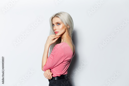 Studio portrait of pretty blonde girl in pink shirt on white background.