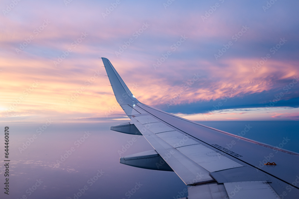 Wing of airplane in colorful cloudscape Wing of airplane in colorful cloudscape