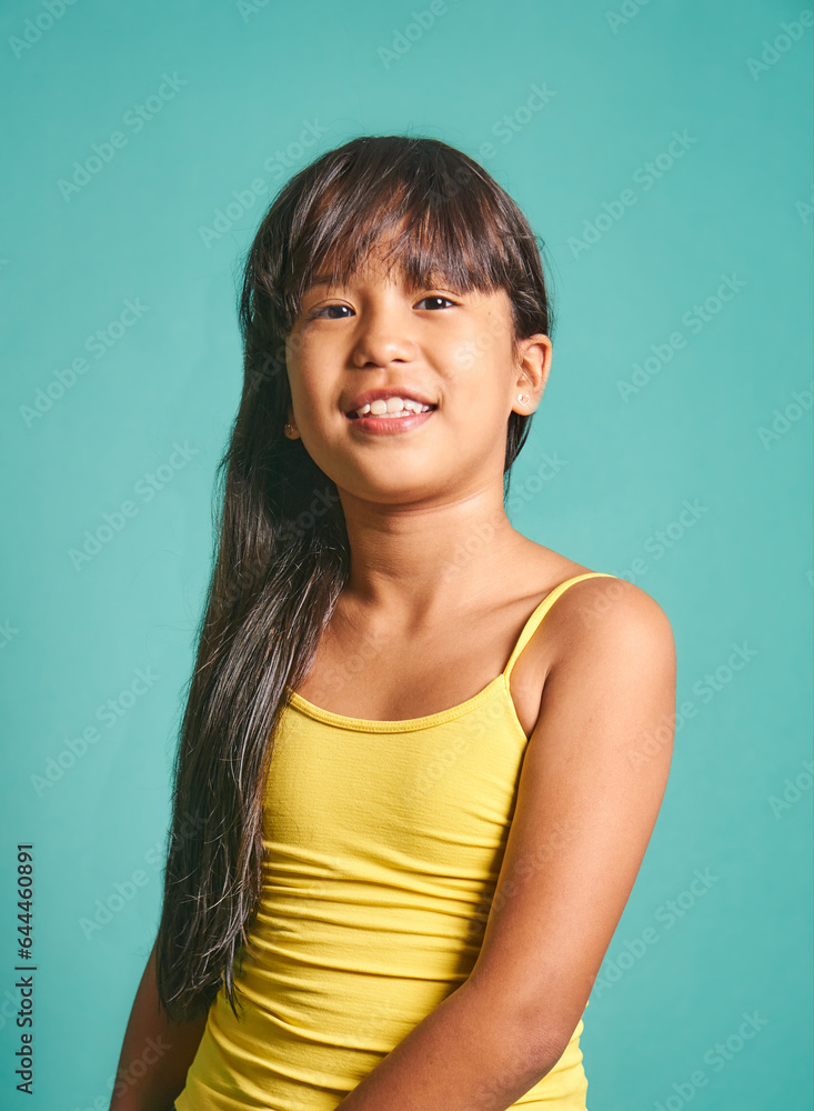 Happy ethnic girl child standing against turquoise backdrop Happy ethnic girl child standing against turquoise backdrop