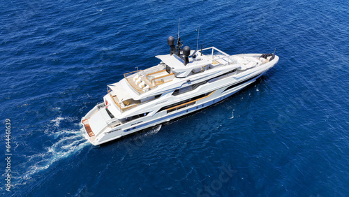 Aerial drone photo of beautiful modern super yacht with wooden deck cruising in low speed deep blue Aegean sea