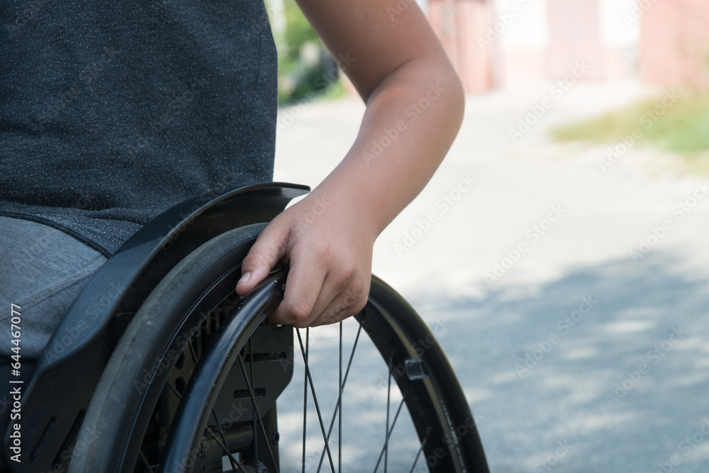 Obraz premium Boy's hand on the wheel of a wheelchair
