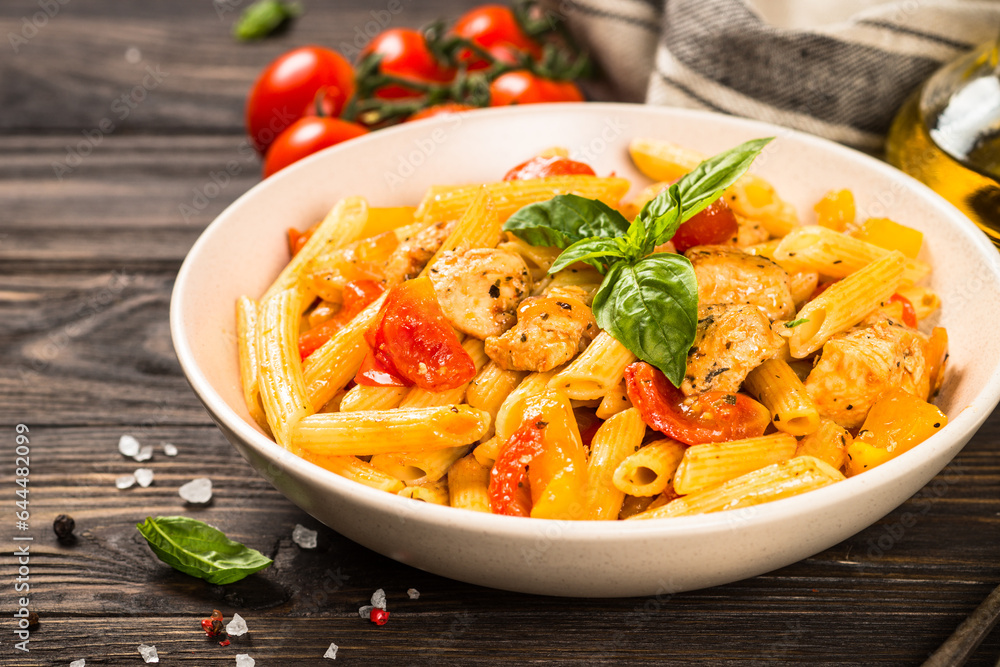 Pasta with chicken and vegetables at wooden table. Traditional italian food. Pasta with chicken and vegetables at wooden table. Traditional italian food.