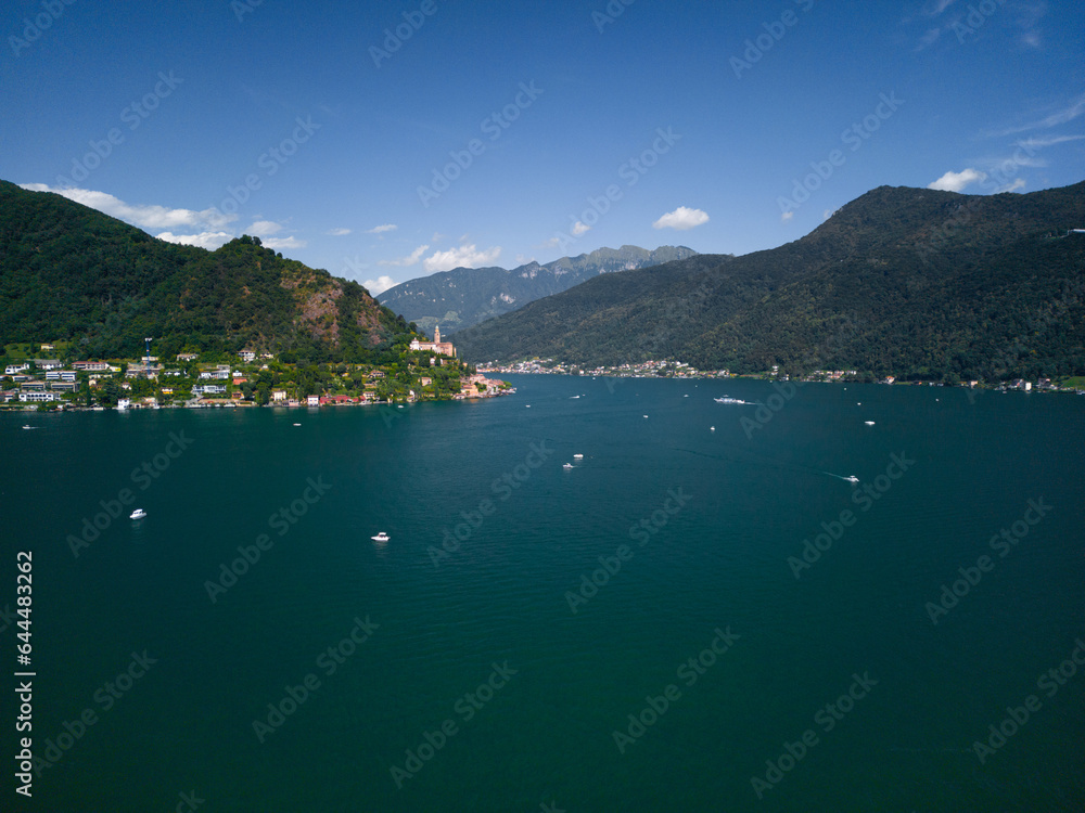 Lake Lugano between italy and switzerland, deep blue lake, day off, yachts on the water, beautiful view, drone footage