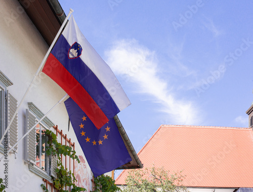 flags of both Slovenia and European Union on the on the wall in sunny day photo