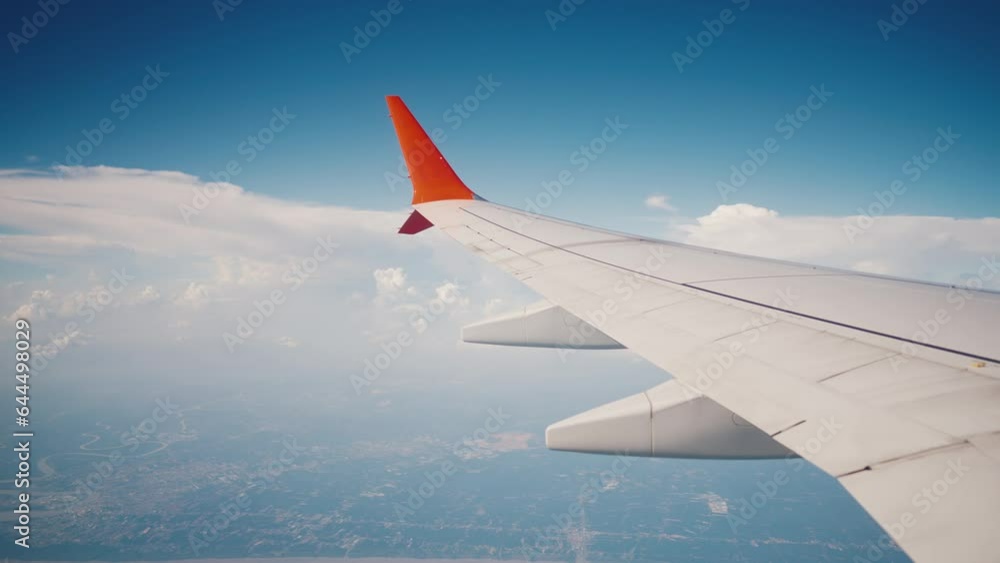 Wing of flying over ocean and island airplane from window on clouds in blue cloudy sky. Aircraft wing in sunny weather in tropics. Passenger jet flight. Travel, tourism, journey, trip, wanderlust. Wing of flying over ocean and island airplane from window on clouds in blue cloudy sky. Aircraft wing in sunny weather in tropics. Passenger jet flight. Travel, tourism, journey, trip, wanderlust.