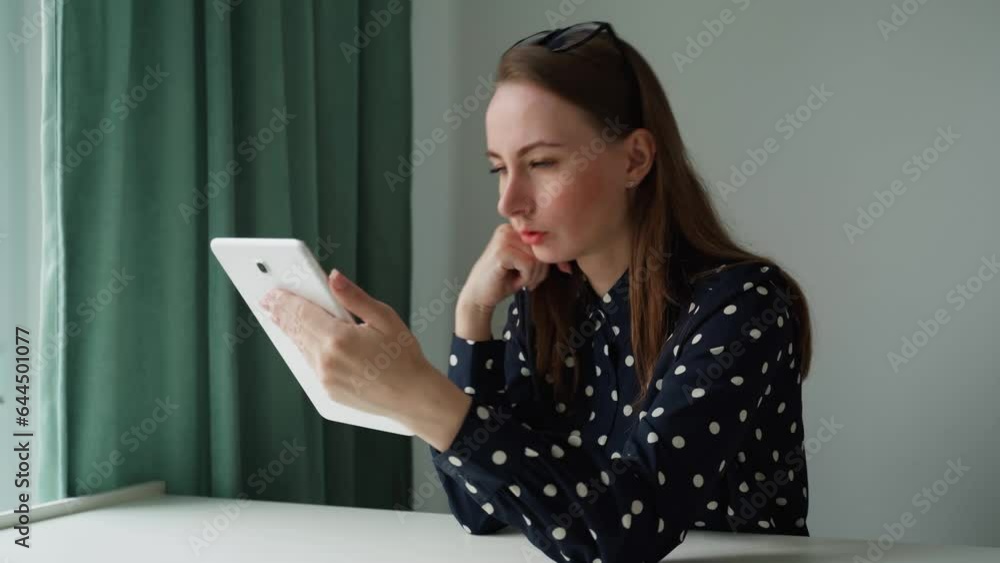 A thoughtful, dreamy, thoughtful young woman using a digital tablet for remote work, freelance work, creative pursuits. A thoughtful, dreamy, thoughtful young woman using a digital tablet for remote work, freelance work, creative pursuits.