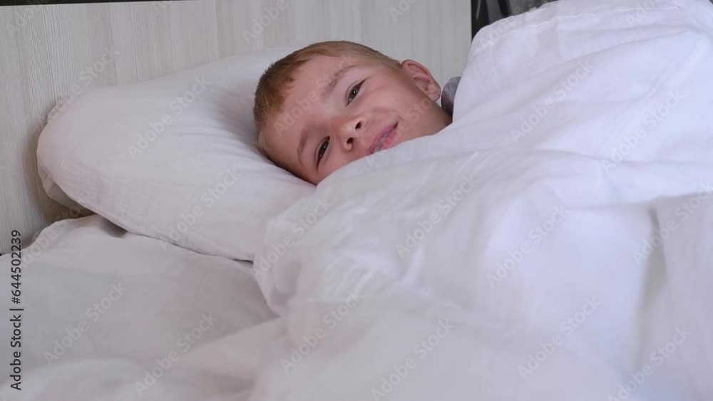 Portrait of a happy Cute funny cheerful little boy in gray pajamas in bed, looking at the camera and laughing. Portrait of a happy Cute funny cheerful little boy in gray pajamas in bed, looking at the camera and laughing.