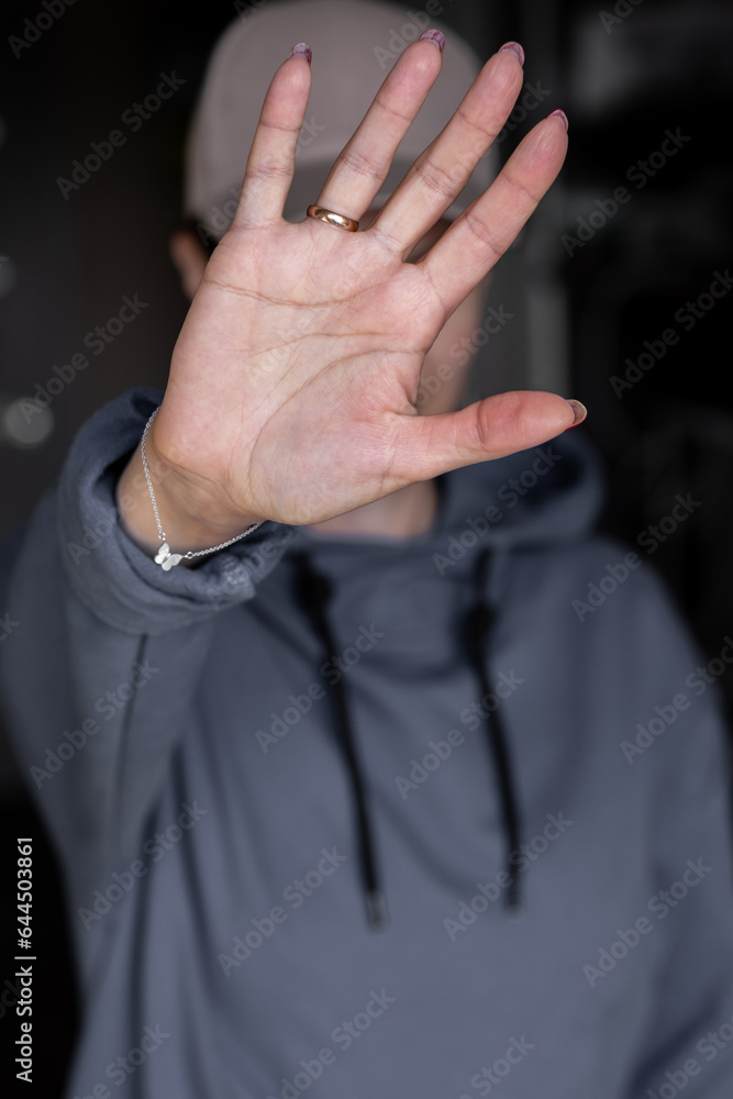 Close-up focus on a woman showing a stop gesture to the camera, blurred background, a strong young woman protesting against domestic violence and abuse, bullying, saying no to gender discrimination Close-up focus on a woman showing a stop gesture to the camera, blurred background, a strong young woman protesting against domestic violence and abuse, bullying, saying no to gender discrimination