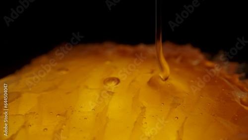 Honey being poured onto golden honeycombs against a black background. Macro Dolly
