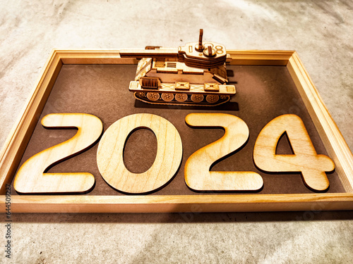 Fotografie Wooden numbers and symbols of new year 2024 with frame and a tank