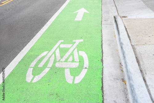 Empty green coloured bicycle lane runnig along a street in a downtown district photo