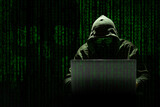 Un hacker encapuchado trabaja en un ciberataque sobre un fondo de código informático donde se aprecia una calavera. Concepto criminalidad de los delitos informáticos en la era digital.