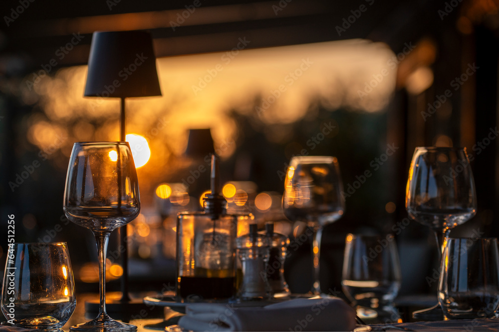 Table à la terrasse d'un restaurant au coucher du soleil - obrazy, fototapety, plakaty 