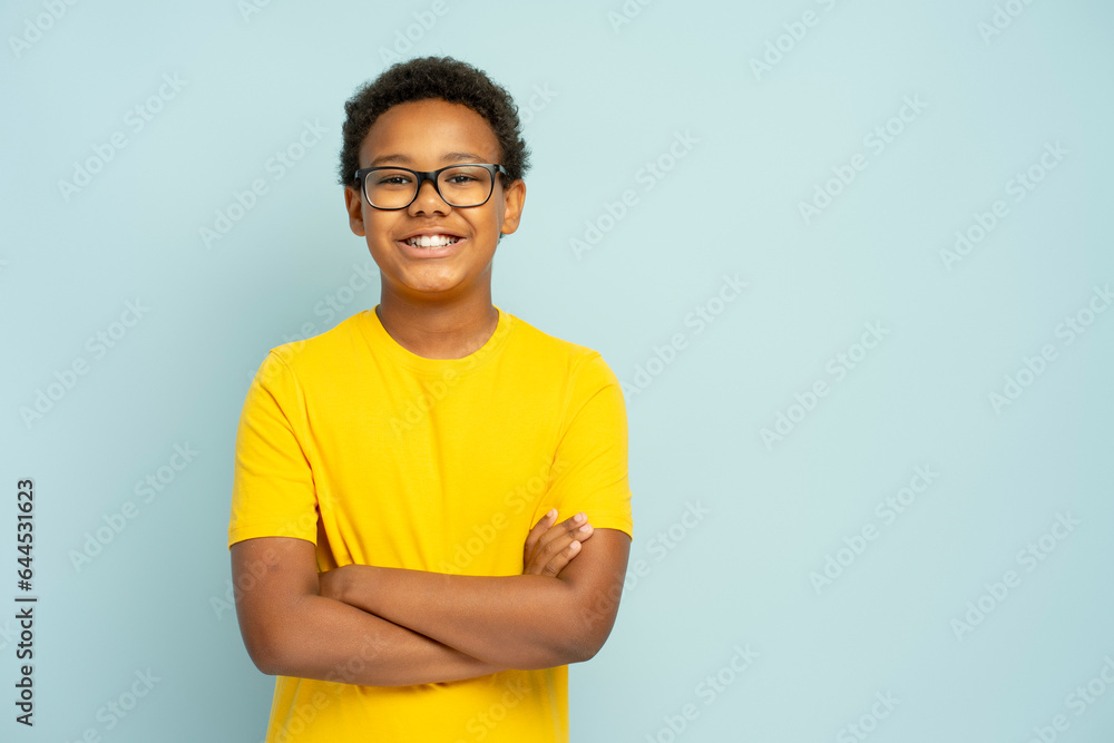 Obraz premium Portrait of smiling African American boy in yellow casual t shirt wearing glasses with crossed arms