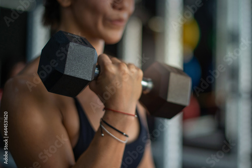 Close up, fitness girl lifting dumbbell weights at the gym, doing exercises with dumbbell, fitness muscular body, selective focus