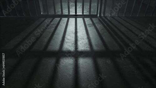 A slow camera pan closeup showing a dimly lit concrete floor of a prison cell and the cast shadows of the jail cell door slamming shut photo