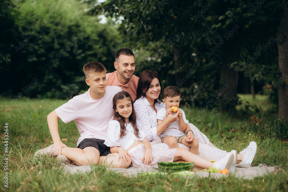 Naklejka premium Happy family having picnic in park on sunny summer day