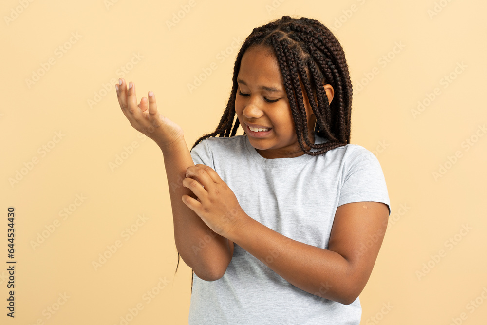 Sad attractive African American girl holding hand, scratch, wound isolated on beige background Sad attractive African American girl holding hand, scratch, wound isolated on beige background