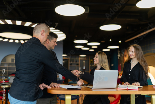 Businessman shakes hands with investor partners in company office. Corporate employees and entrepreneur negotiate about investing