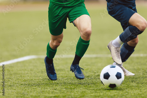Fototapeta Naklejka Na Ścianę i Meble -  Adult football competition. Soccer football player dribbling a ball and kick a ball during match in the stadium. Footballers in action on the tournament game.