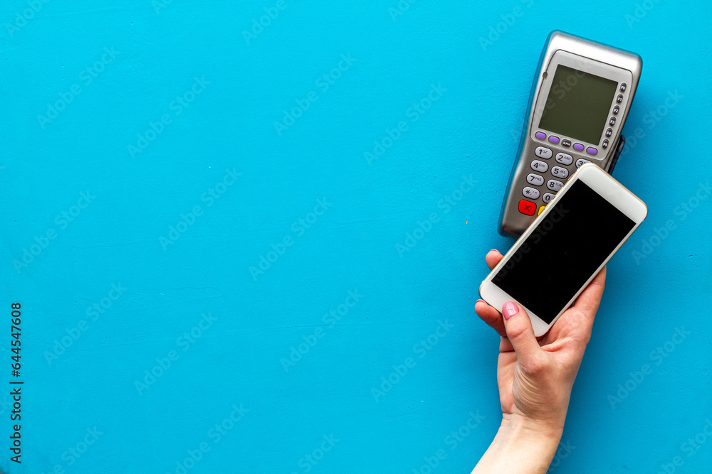 Payment by mobile phone pay. Female hand with mobile phone near POS payment terminal Payment by mobile phone pay. Female hand with mobile phone near POS payment terminal