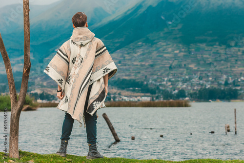 Model wearing a poncho handmade with sheep cloth by the indigenous Kichwa artisan communities of the area, posing at the San Pablo lake in Otavalo, Ecuador. photo
