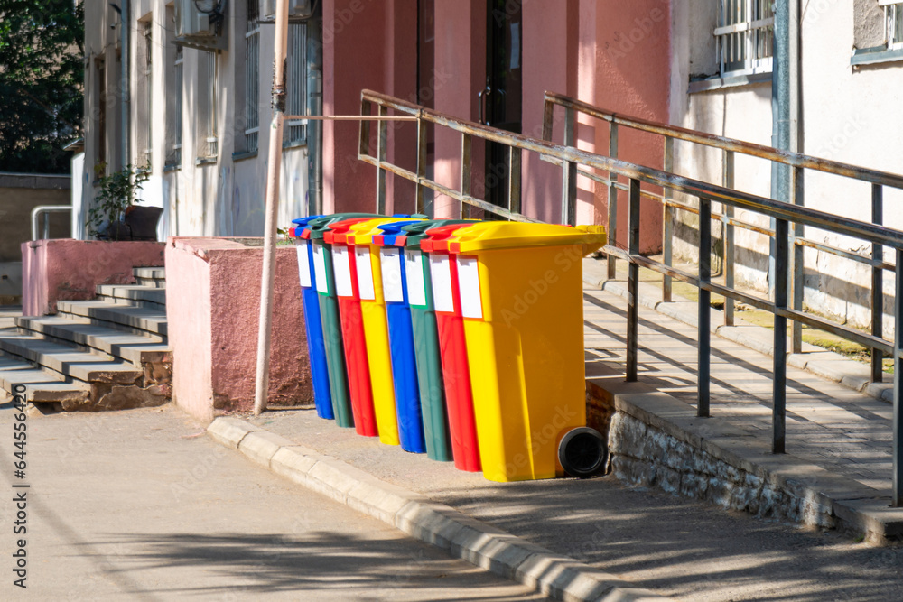 Garbage trash bins multicolor red, yellow, green, blue in school yard for waste management