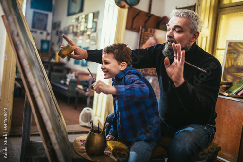 Father and son working and painting together in art studio