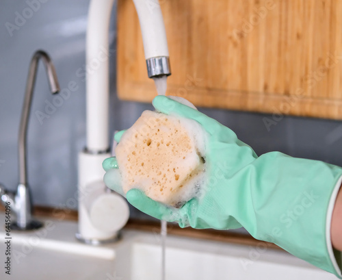 Wash the sink with a damp sponge and soap. Hand in a household glove with a sponge. Wet cleaning of the house. Cleaning plumbing. Close angle of home cleaning kitchen.