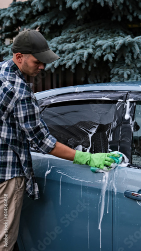 a man washes a car with foam. washing the car with a special tool for washing the car. foam sponge photo