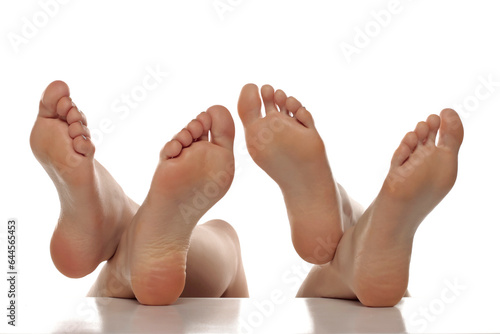 Two pairs od a beautiful well-groomed women's sole feet close-up on a white isolated background, The concept of foot skin care photo