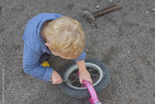 a boy child repairs a bicycle wheel with a wrench, photo without filters