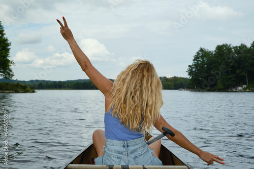 Mujer en canoa en un lago con los brazos estirados y el pelo suelto