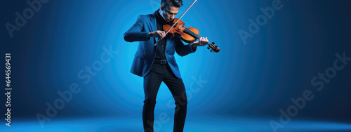 Young man playing violin on blue background