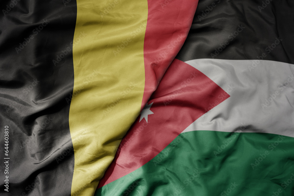 big waving national colorful flag of belgium and national flag of jordan .