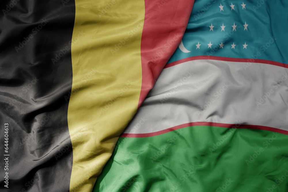 big waving national colorful flag of belgium and national flag of uzbekistan .