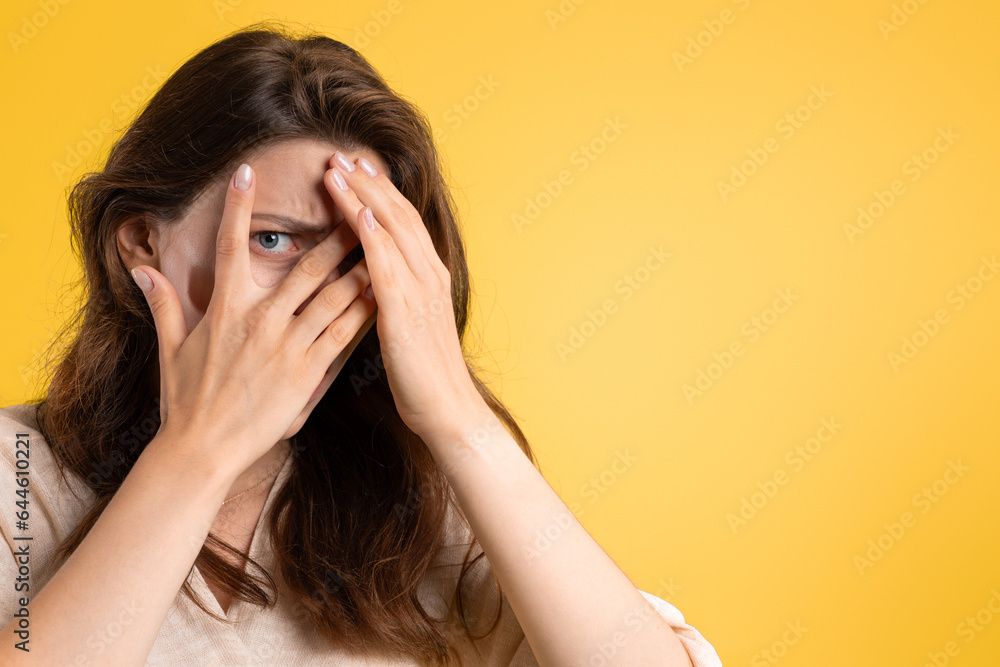Scared young caucasian lady covers her face with hands, afraid, isolated on yellow studio background Scared young caucasian lady covers her face with hands, afraid, isolated on yellow studio background