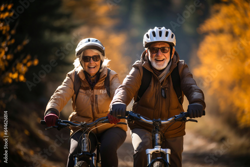 Happy mature couple riding bikes in helmets, bicycles in park. Cheerful active senior couple with bicycle in public park together having fun lifestyle. Safe and perfect activities for elderly people