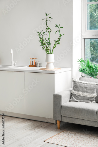 Vase with bamboo stems on table in kitchen